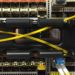 Close-up of a network switch with yellow fiber patch cables crossing between rack rails