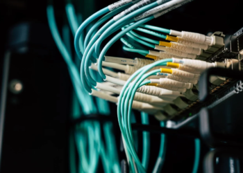 Close-up of teal fiber optic cables plugged into a Cisco Nexus network switch