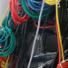 Tangled colored network patch cables running into a server rack panel