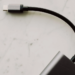 Braided USB-C cable plugged into a small black device on a marble surface