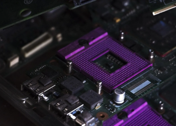 Purple CPU socket with empty die cavity on a dark green motherboard