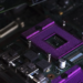 Purple CPU socket with empty die cavity on a dark green motherboard