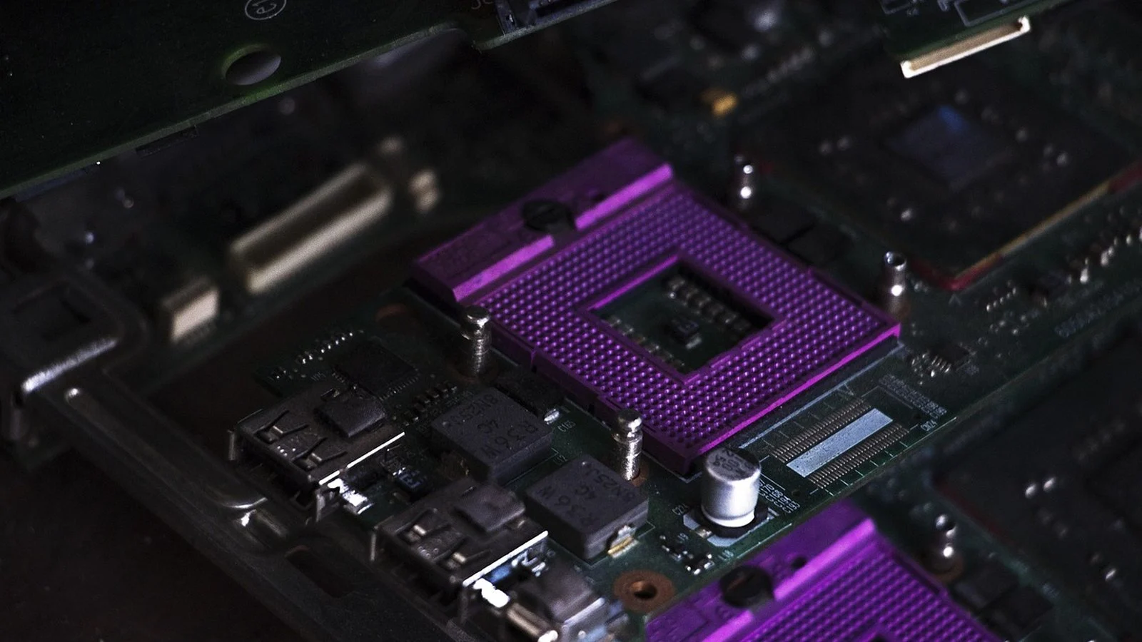 Purple CPU socket with empty die cavity on a dark green motherboard