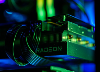 A Radeon graphics card installed in a PC case, lit by green and blue ambient light