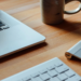 MacBook, wireless keyboard, trackpad, and a ceramic mug on a wooden desk