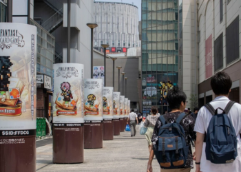 Street-side cylindrical pillars advertising Final Fantasy Digital Card Game in a Japanese shopping district