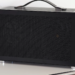 Black mesh-paneled mini-PC with leather carry handle on a white table, side panel closed