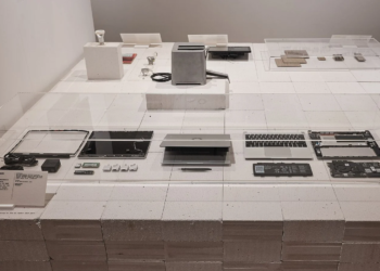 Disassembled Framework Laptop parts displayed in a museum exhibit case on pricing repairability