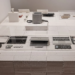 Disassembled Framework Laptop parts displayed in a museum exhibit case on pricing repairability