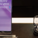 Samsung Galaxy S26 Ultra on a store display stand beside a Samsung earbuds case, purple lock screen lit