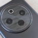 Macro shot of a phone's dark gray circular rear camera module with four lenses on a textured table