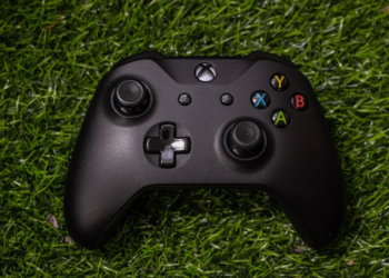 Black Xbox wireless controller resting on artificial turf grass