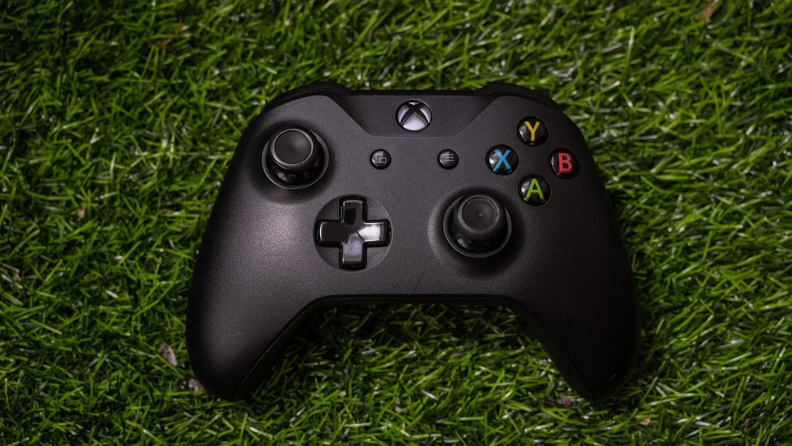 Black Xbox wireless controller resting on artificial turf grass