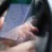 Blurred photo of a hand holding a phone showing a map route while driving a car