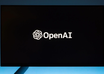 Computer monitor on a blue background displaying the OpenAI logo and wordmark
