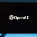 Computer monitor on a blue background displaying the OpenAI logo and wordmark