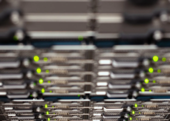 Close-up of server rack with blinking green status LEDs, blurred foreground and background