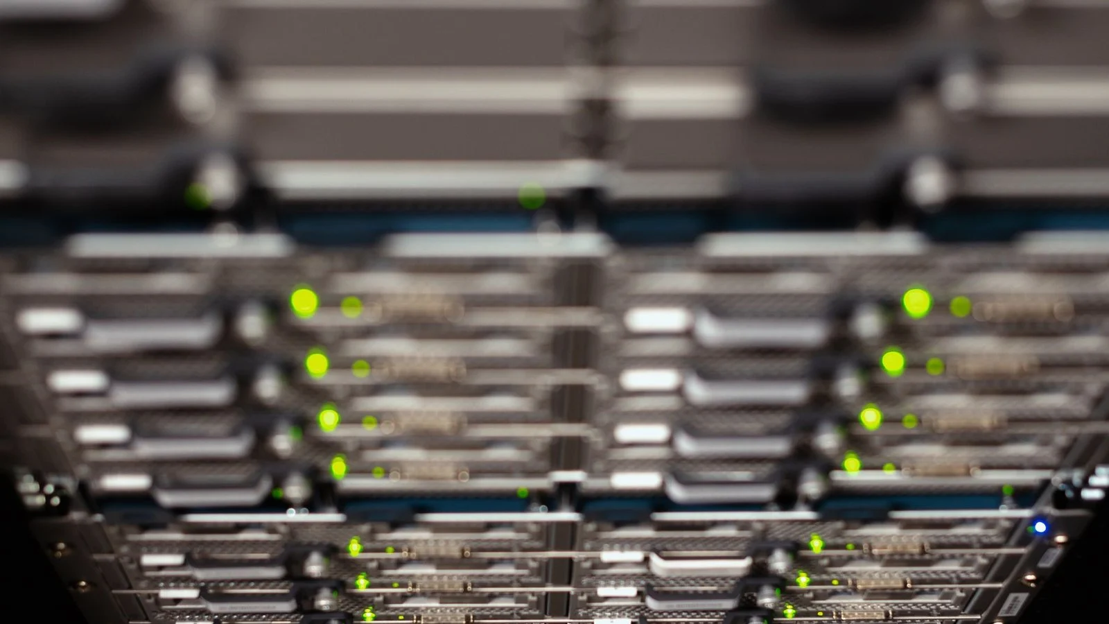 Close-up of server rack with blinking green status LEDs, blurred foreground and background