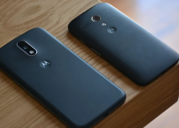 Two dark-colored older Motorola phones lying face-down on a wooden surface