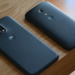 Two dark-colored older Motorola phones lying face-down on a wooden surface