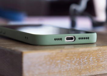 Close-up of a green-cased smartphone's USB-C port edge resting on a wooden table