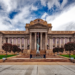 Neoclassical courthouse building with columned facade and Statue of Liberty replica on lawn