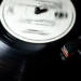 Black vinyl record spinning on a turntable with tonearm and stylus lowered, no visible branding