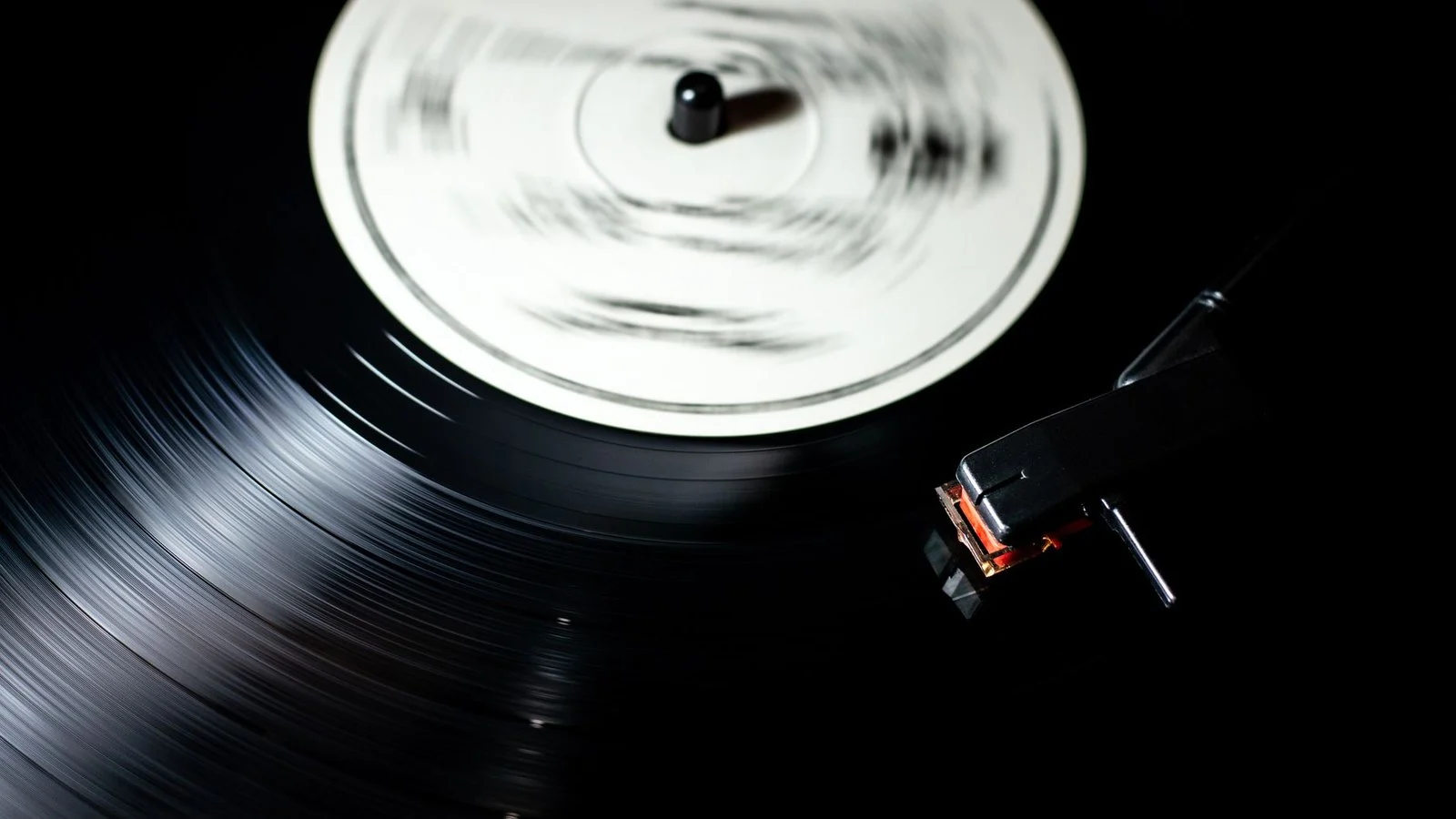 Black vinyl record spinning on a turntable with tonearm and stylus lowered, no visible branding