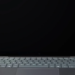 Dark gray laptop with screen off, HP logo on bottom bezel, keyboard and trackpad visible, on wood desk