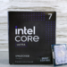 Boxed Intel Core Ultra 7 265KF processor beside its LGA1851 chip on a wood-and-concrete backdrop
