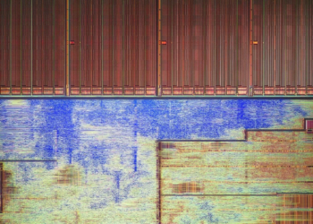 Extreme macro shot of bare silicon die circuitry with copper-toned traces and a blue-tinted region