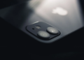 Close-up of an iPhone's glass back and dual rear camera lenses lit from above