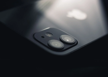 Close-up of an iPhone's glass back and dual rear camera lenses lit from above