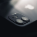 Close-up of an iPhone's glass back and dual rear camera lenses lit from above