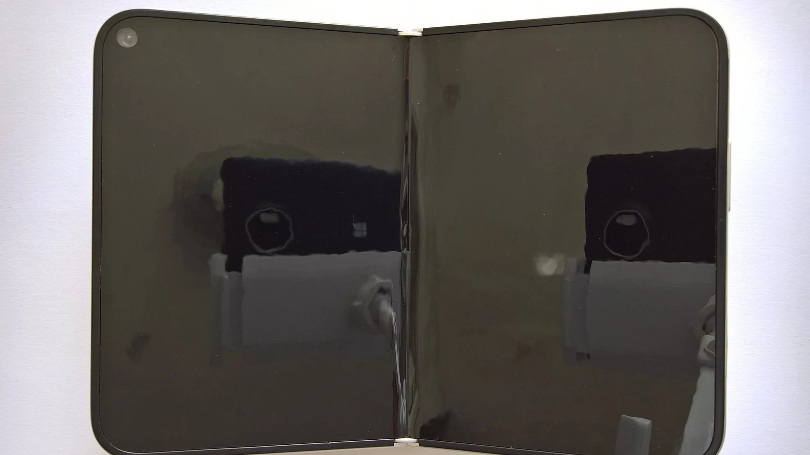 White folding smartphone open flat with two dark reflective screens joined by a hinge