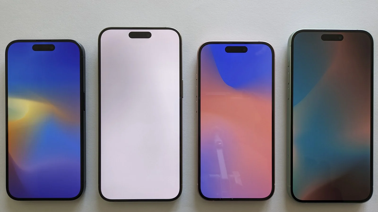 Four flat iPhones with different screen colors lined up side by side, screens on