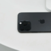 Black iPhone lying face-down on a white surface, showing triple-lens camera and Apple logo