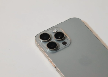 Close-up of a silver smartphone's triple-lens camera module, appearing detached from its housing, on a white surface