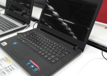 Black Lenovo IdeaPad 110 laptop displayed open on a store shelf beside other laptops