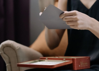 Woman holds a gray card over an open red Villars chocolate tin