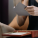 Woman holds a gray card over an open red Villars chocolate tin