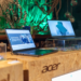 Acer laptops on display at an Intel-branded event booth with green plant decor