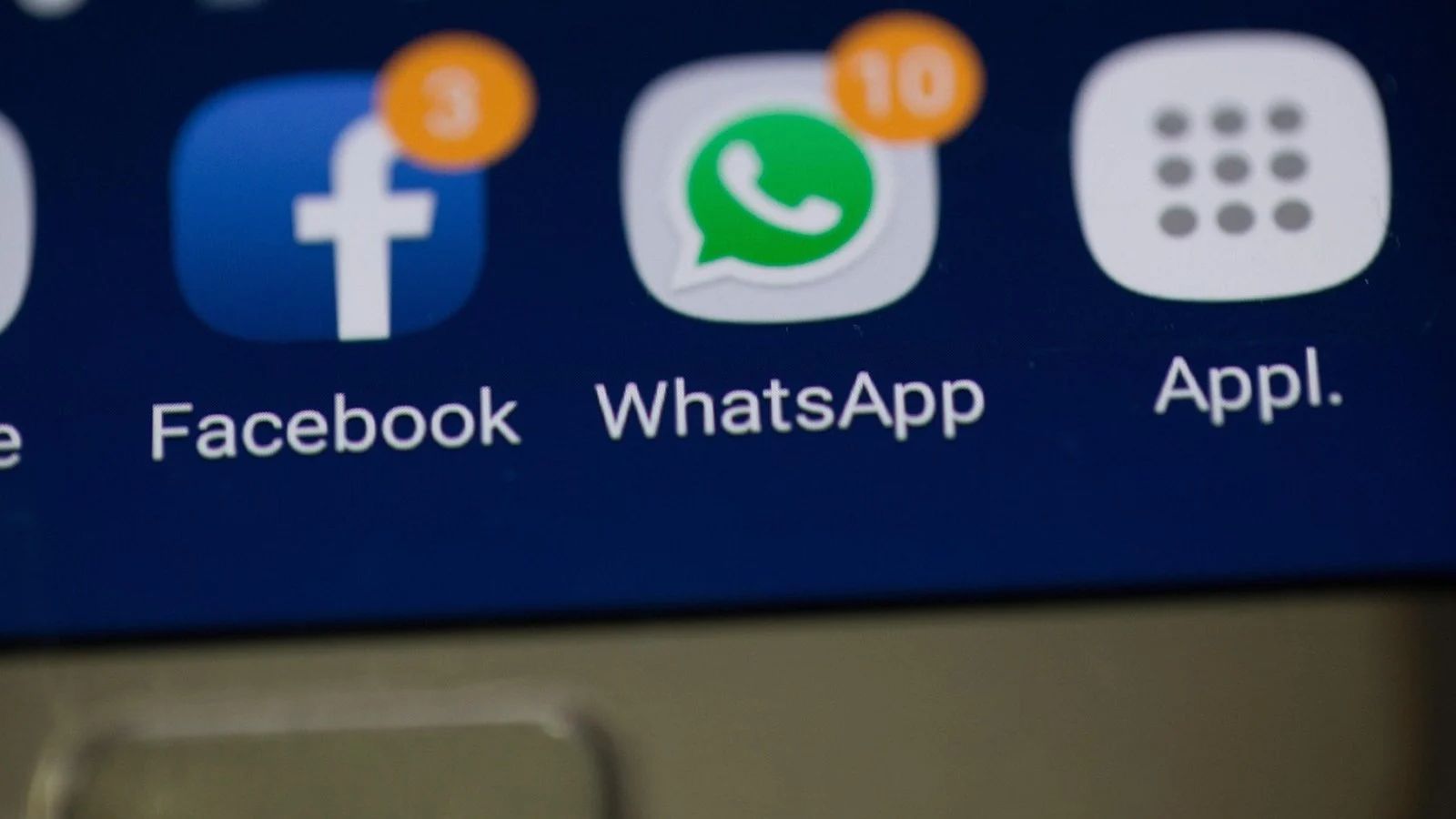 Close-up of a phone screen showing Facebook and WhatsApp app icons with notification badges