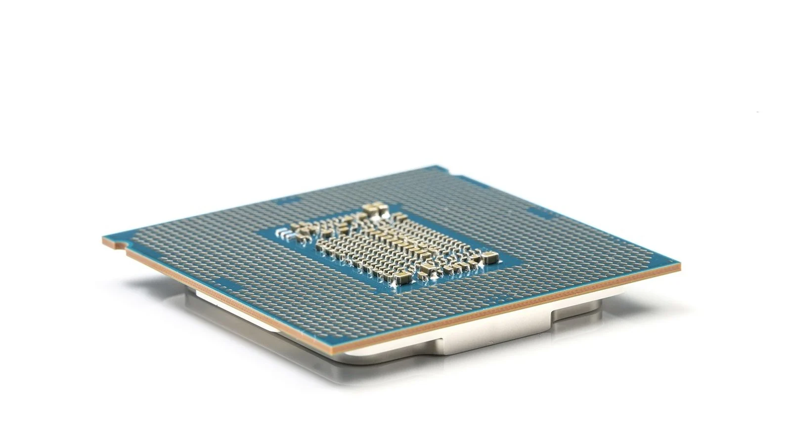 Underside of a CPU package showing the pin substrate and gold contact pads on a white background