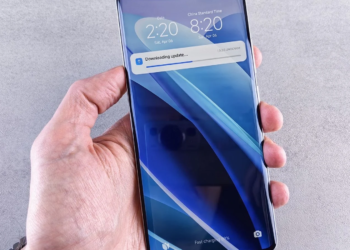 Hand holding a smartphone showing a lock screen update download progress bar