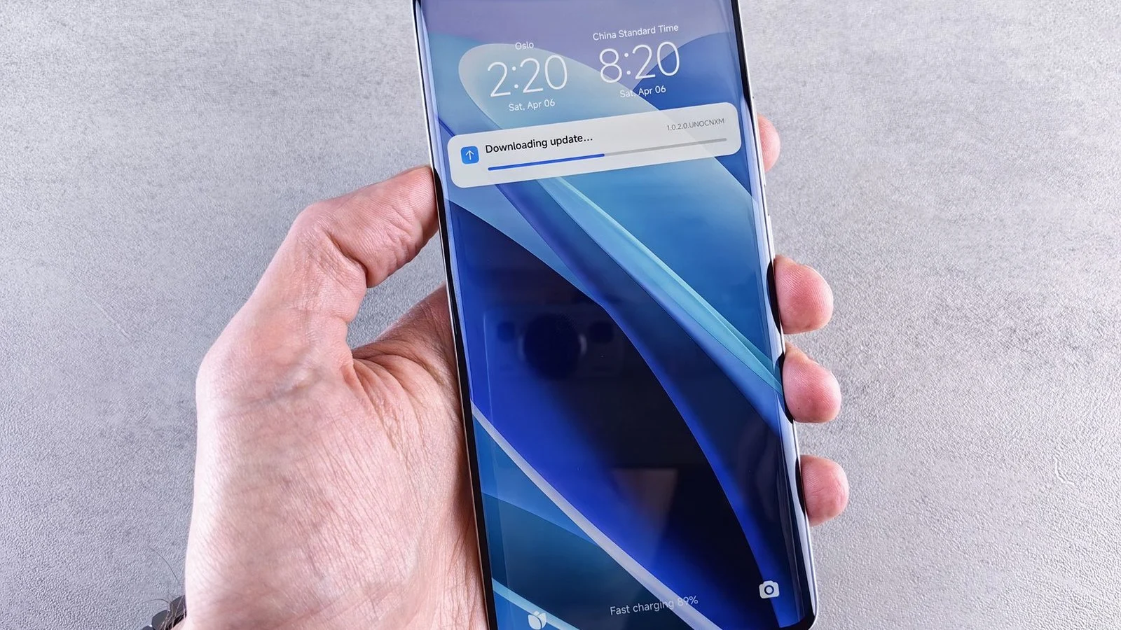 Hand holding a smartphone showing a lock screen update download progress bar