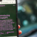 Hand holds a phone showing OpenAI's 'Introducing ChatGPT' blog post in a browser