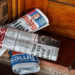 Rolled newspapers, including Sunday Times and Business Times, stacked on a wooden doorstep