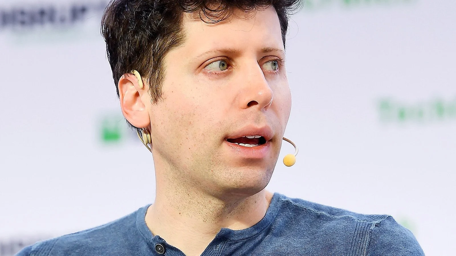 Man speaking into a headset microphone at a conference panel