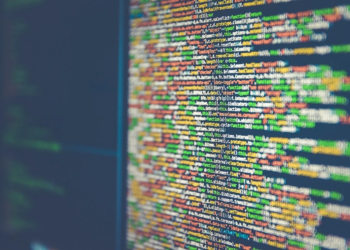 Blurred dark computer monitor showing lines of colorful JavaScript source code